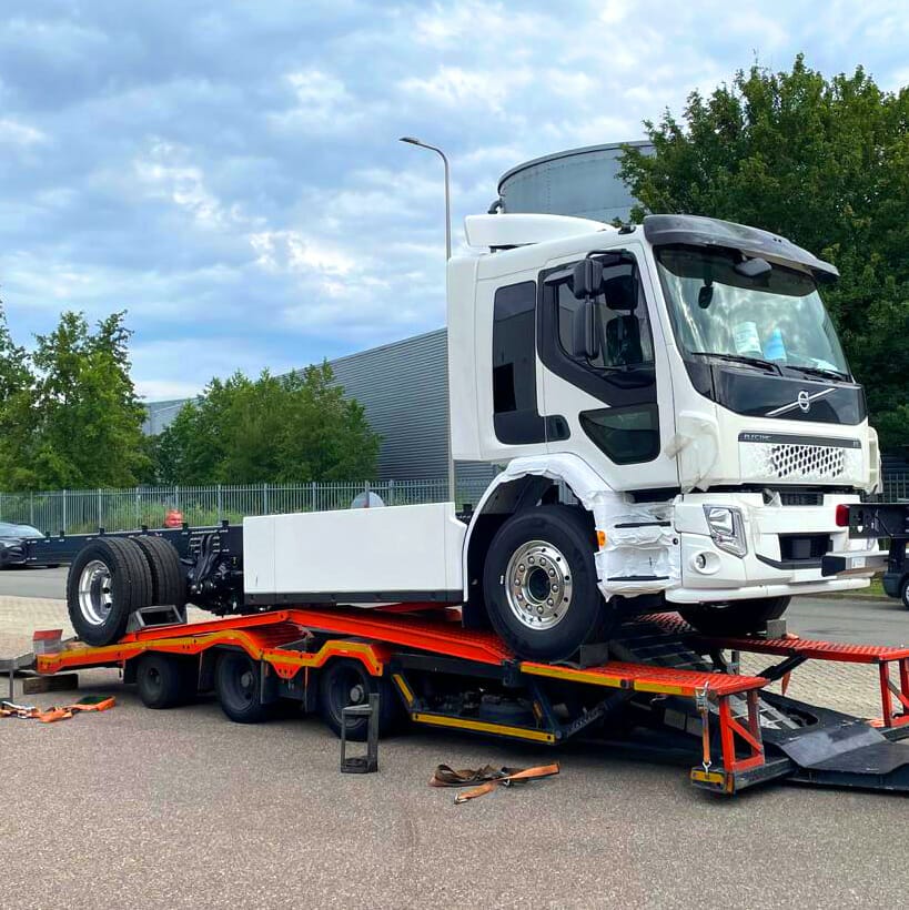 De nieuwe elektrische vrachtwagen Volvo FE Electric. De wagen is wit en staat nog op de oranje trailer waarmee hij afgeleverd is.